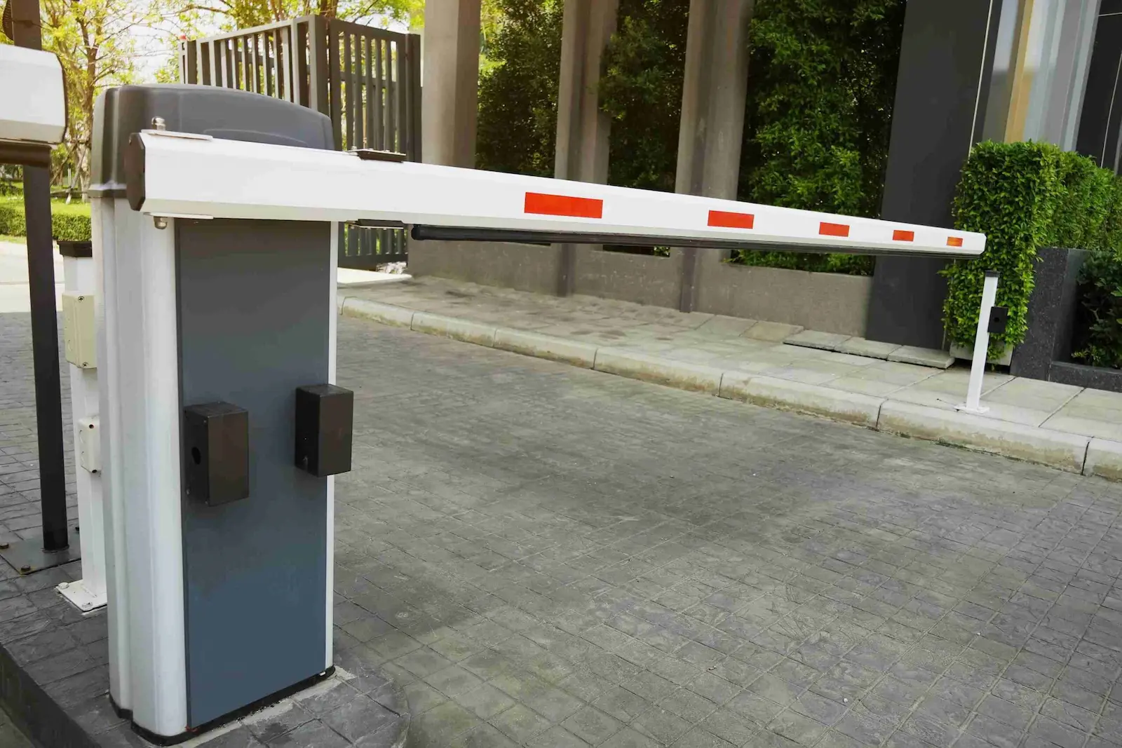 Automated white boom barrier at a commercial building vehicle entrance